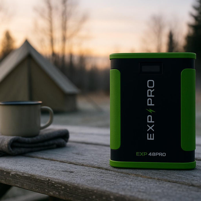 EXP48PRO APEX portable CPAP battery standing on a camp table at a frosty campsite at dawn, with frost on the table and a tent in the background.