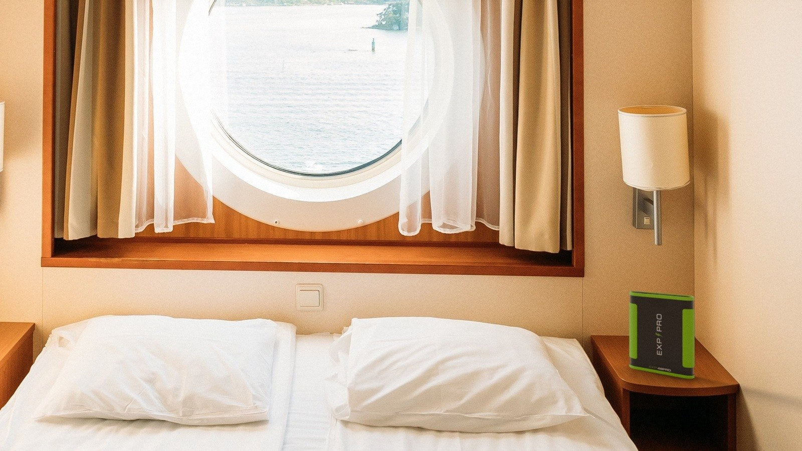 EXP48PRO APEX CPAP battery on the nightstand of a cruise ship cabin, with the sea through the porthole.