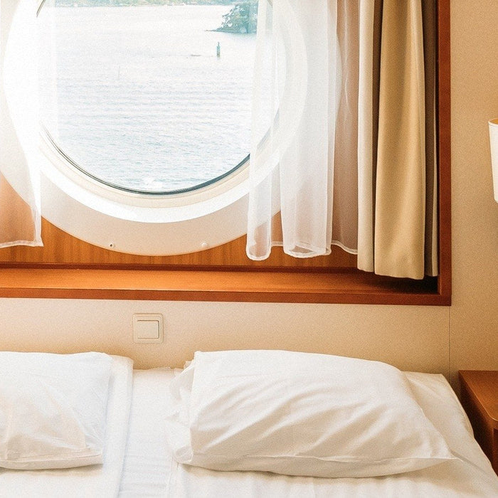 EXP48PRO APEX CPAP battery on the nightstand of a cruise ship cabin, with the sea through the porthole.